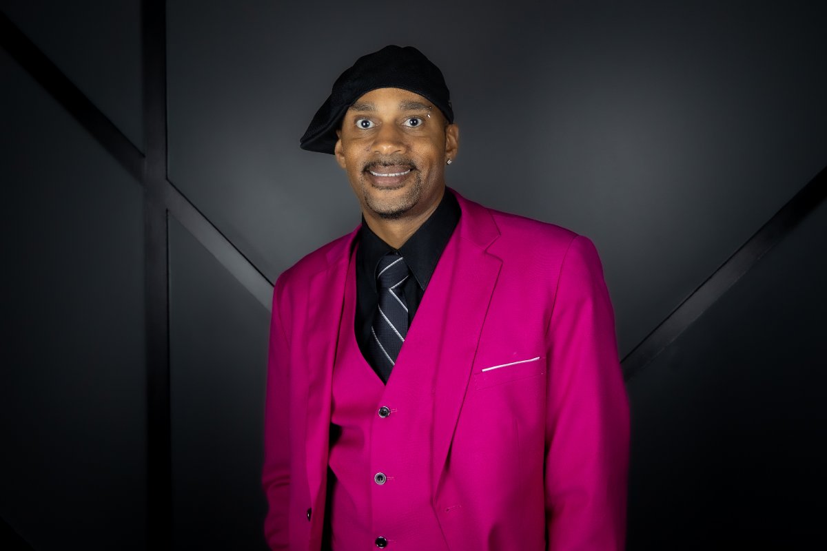 Mathew Goings — Matty G — founder and CEO of Optimistic Media, in a magenta suit and black cap